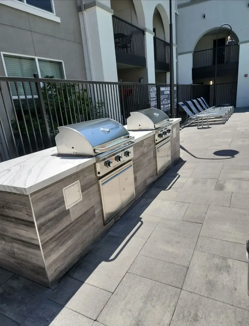 Custom outdoor BBQ kitchen with twin grills and marble counters